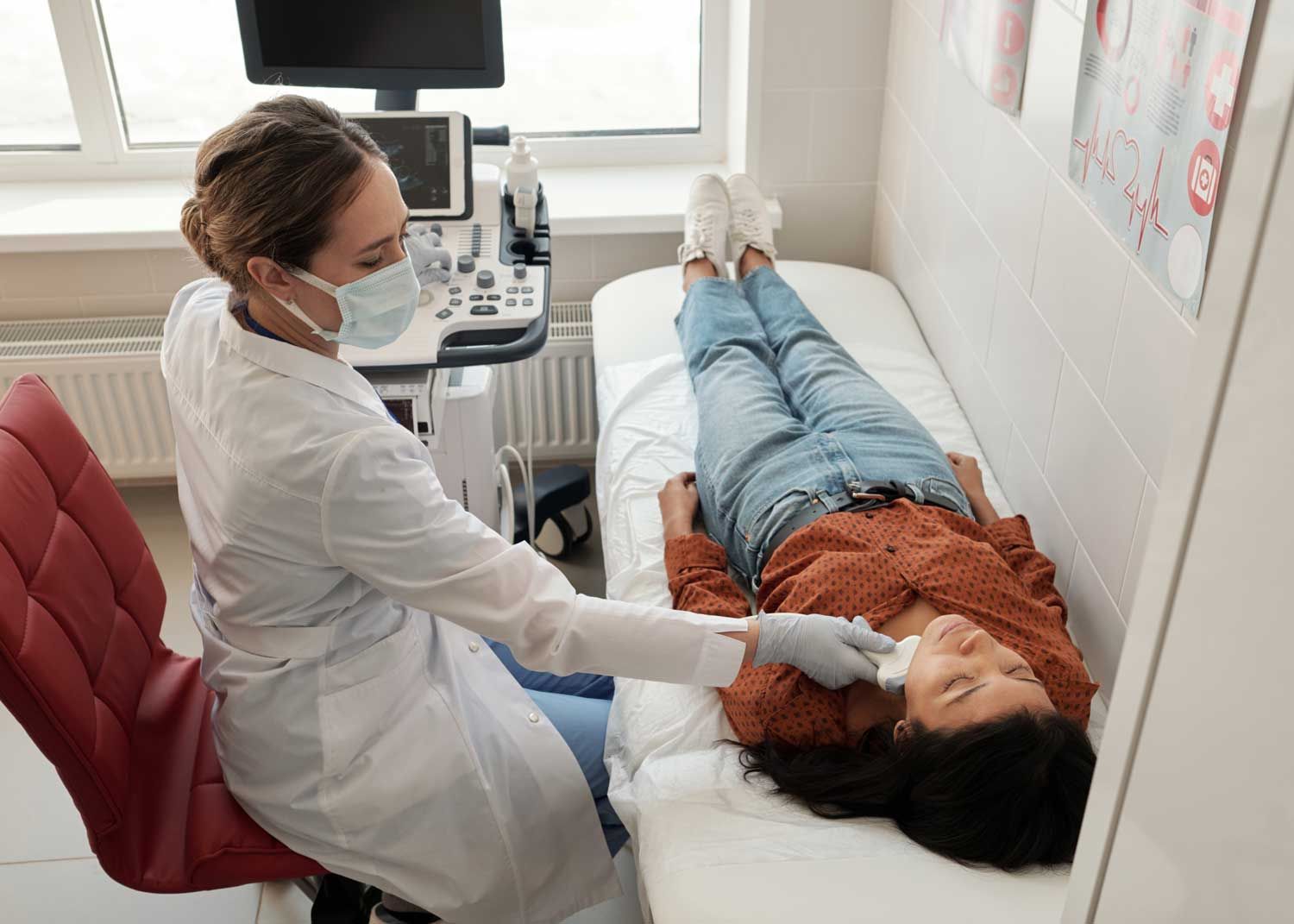 A woman sits on an exam table and talks to a nurse