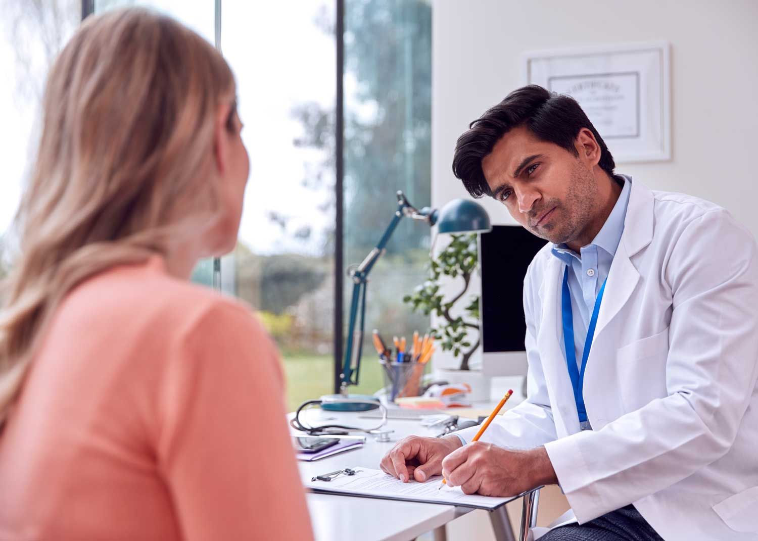 A woman sits on an exam table and talks to a nurse